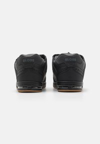 Black athletic shoes featuring a textured leather and mesh upper, padded collar, and a rubber sole with visible air cushioning units.