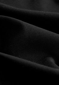 Black fabric showcasing a smooth, slightly textured surface with fine ribbing, draping gently in layered folds.