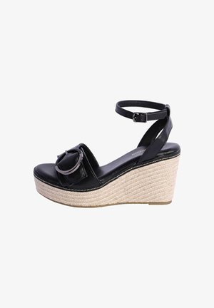 Sandalia cuña de cuero negro con tira en el tobillo, hebilla grande en la parte delantera y suela de plataforma tejida y texturizada.