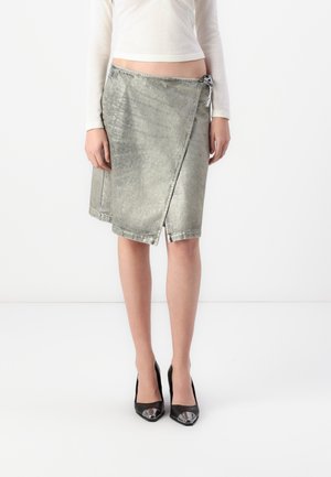 Silver metallic denim wrap skirt with a raw hem, featuring a side tie and a mid-length cut. Worn with black patent leather heels.