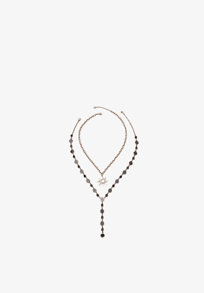 Deux colliers dorés ; l'un avec un pendentif en forme de soleil et l'autre avec des perles rondes noires et grises disposées en forme de Y.