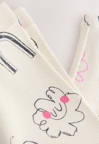 Tessuto a coste color crema chiaro con illustrazioni nere e rosa di forme astratte e disegni, inclusa una decorazione floreale con accenti rosa.