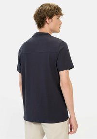 Marineblauwe polo met korte mouwen en een klassieke kraag, voorzien van een zachte textuur en een subtiele naaddetail over de bovenrug.