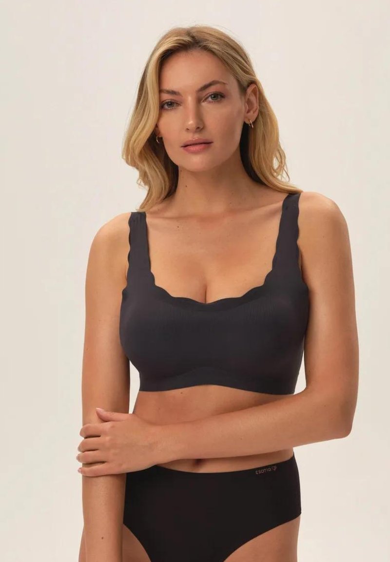 Czarny ribbed braletka z falbaniastymi krawędziami, regulowanymi szerokimi ramiączkami i bezszwowym designem. W połączeniu z czarnymi majtkami bikini.