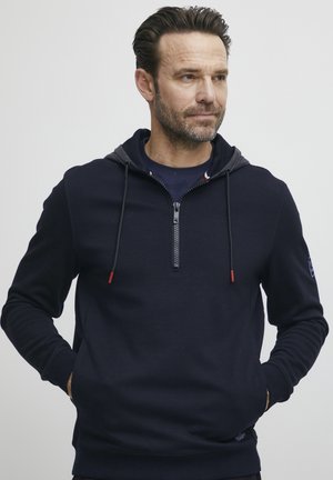 Navy pullover hoodie with a half-zip front, drawstring hood, and red accents. Soft fabric and ribbed cuffs and hem for a snug fit.