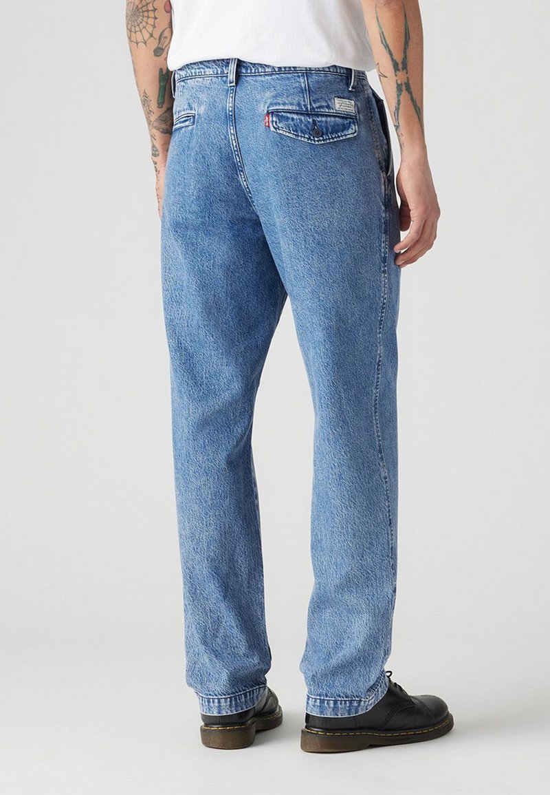 Hellblaue Jeans aus Denim mit lockerer Passform, fünf Taschen und subtiler Verwaschung. Verfügt über hintere Taschen mit Markentags und sichtbaren Nähten.