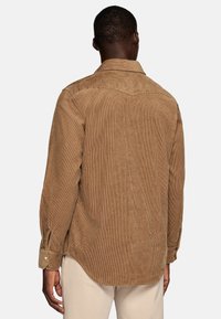 Bruine corduroy shirt met verticale ribben, knoopmanchetten en een afgeronde zoom, met een klassieke kraag en een ontwerp met een achterpiece.