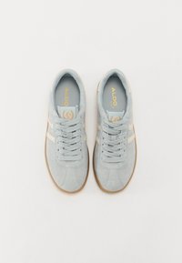 Baskets en daim bleu clair avec des accents blancs, des lacets plats et des semelles en caoutchouc naturel. Elles présentent un logo sur la languette et les côtés.