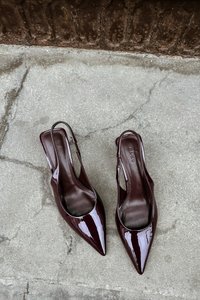 Burgundijas lakota āda slingback apavi ar norādītām purngalām, atvērtām sāniem un gludu, spīdīgu apdari. Līdzenais papēdis un iešūta logo uz iekškārtas.