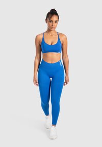 Sujeción deportiva azul y leggings hechos de una tela suave y elástica, con un diseño ajustado que presenta un logo sutil en la cinturilla.
