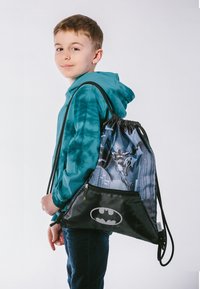 Kordeltasche mit Batman-Design, schwarzem Grund, blauem gemustertem Hintergrund, aus leichtem Stoff, mit einem Reißverschlussfach.