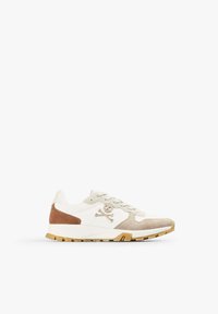 White sneaker with tan suede accents, textured fabric, and light green eyelets. Features a logo with a skull and crossbones. Rubber sole.