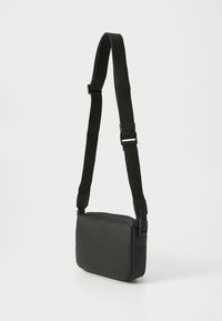 Black leather crossbody bag with adjustable black strap, rectangular shape, textured surface, and minimalistic design.