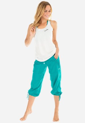 White sleeveless tank top with black logo and teal cropped pants with drawstring cuffs; smooth fabric; casual, comfortable fit.