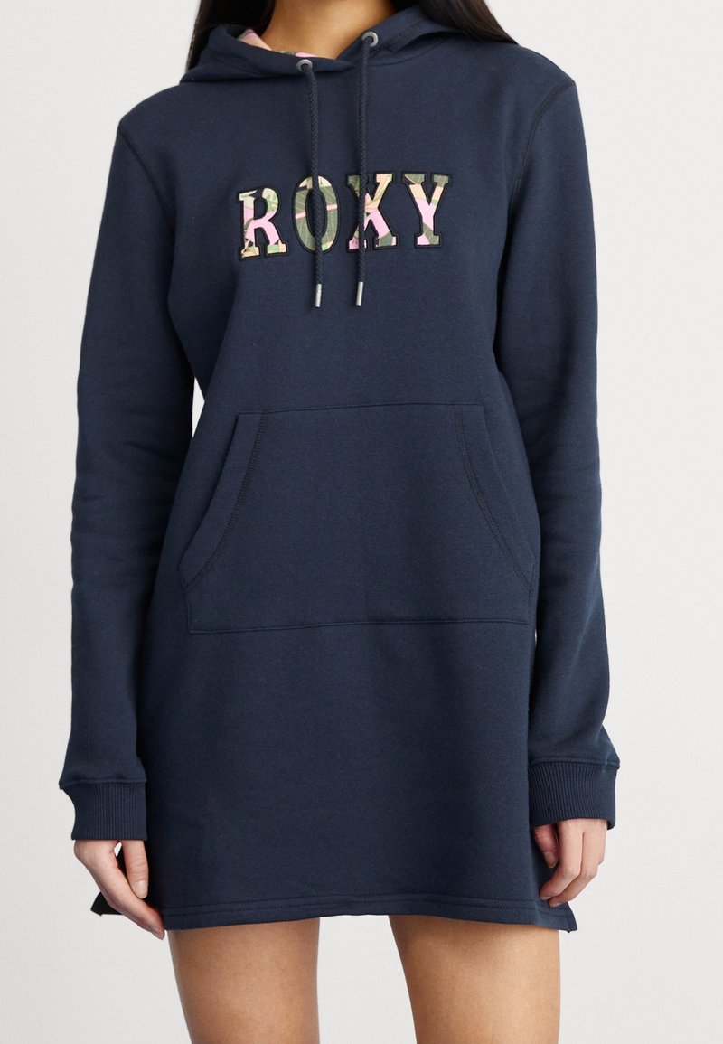 Navy blue sweatshirt dress made of cotton blend. Features a hood, front pocket, and "ROXY" logo with camouflage pattern, long sleeves.