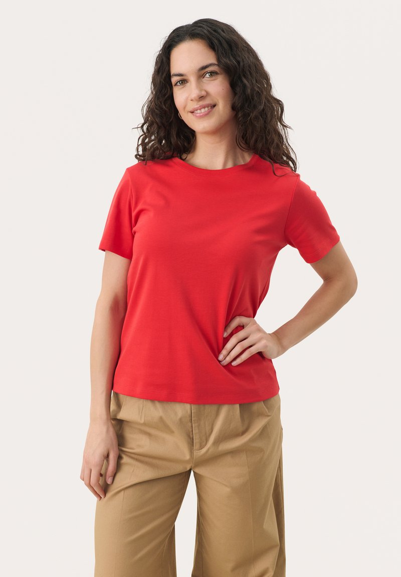 T-shirt rouge à manches courtes avec un col rond, fabriqué en tissu doux. Assorti à un pantalon large beige clair. Design simple et ajusté.