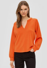 Oranje sweatshirt met V-hals, lange mouwen en gathered boorden. Gemaakt van een soepele stof met een relaxte pasvorm.