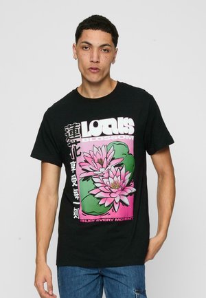 Black cotton t-shirt featuring a pink lotus flower graphic, bold white text, and green accents. Casual fit with a round neckline.