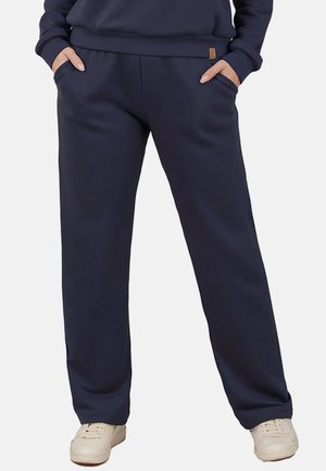 Marineblaue Sweatpants mit lockerer Passform, seitlichen Taschen und einem glatten Stofftextur. Abgerundet mit einem kleinen Markenetikett am Bund.