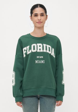 Žalias džemperis su užrašu "FLORIDA" ir "MIAMI" balta spalva. Laisvas kirpimas, apvalus iškirpimas, ilgos rankovės su baltomis detalėmis ant rankogalių.