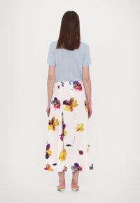 Lichtblauw, kortemouwtop met een witte, midi rok met bloemenprint, versierd met kleurrijke bloemen en een vloeiende uitstraling.