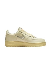 Sneaker in pelle color crema con punta rotonda, logo swoosh in argento, suola in gomma, parte superiore perforata e chiusura con lacci.