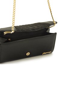 Zwarte handtas met een gequilt textuur aan de bovenkant, gouden kettingstrap en een magnetische sluiting. Voorzien van een ruime binnenkant met een ritsvak.