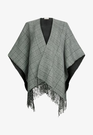 Schwarzer und weißer gemusterter Poncho mit fransigem Saum, aus einem weichen Material gefertigt. Offenes Design mit V-Ausschnitt und weiten Ärmeln.