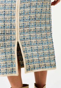 Gewebter Rock in Blau und Beige mit einem strukturierten Muster und einem seitlichen Schlitz. Verfügt über einen kontrastierenden Besatz entlang der Kante für zusätzliche Details.