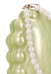 Zelený doplněk ve tvaru mušle s lesklým povrchem, zdobený bílými perlovými korálky kolem okraje a zapínáním ze zlatého kovu.