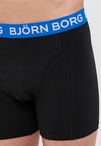 Black boxer briefs with a blue elastic waistband featuring the brand name "BJÖRN BORG" in white letters. Smooth texture and fitted design.