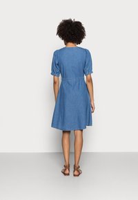 Denimmekko lyhyillä puff-hihnoilla, tiukalla vyötäröllä ja levenevällä helmaa. Ominaisuuksiin kuuluu pyöreä pääntie ja yksivärinen sininen väri.