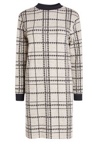 Robe à manches longues en tissu maille beige avec un motif à carreaux noirs. Elle possède un col rond et des poignets côtelés noirs.