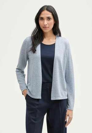 Světle modrý cardigan s jemnou texturou, otevřeným předním designem, dlouhými rukávy, který je kombinován s tmavě modrým topem a elegantními tmavě modrými kalhotami.