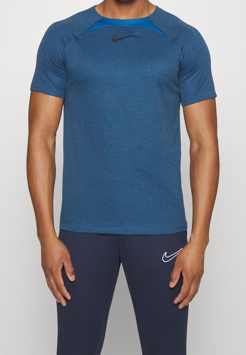 Camiseta deportiva azul de manga corta, con tejido que absorbe la humedad, cuello redondo y logotipo negro de Nike en el pecho. Presenta un diseño texturizado.