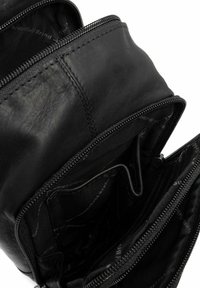 Interno di una borsa in pelle nera con multiple tasche con zip, caratterizzato da una texture liscia e una fodera in tessuto stampata con il logo.