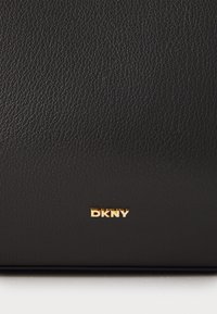 Black textured leather handbag featuring a gold "DKNY" logo. Simple, rectangular shape with minimal hardware and no distinct patterns.