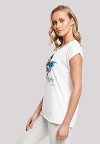 White cotton t-shirt with rolled sleeves, featuring a colorful Wonder Woman graphic printed on the front. Soft texture, relaxed fit.