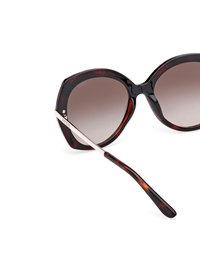 Occhiali da sole oversize in tartaruga con lenti sfumate, montatura a motivo nero e marrone, sottili dettagli metallici sulle aste e texture liscia.