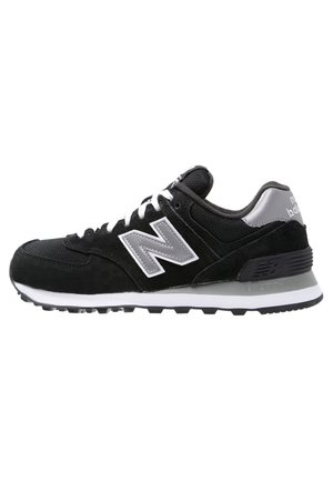 Sort og grå New Balance sneaker med hvide snørebånd og logo, polstret sål og mesh- og ruskindsoverdel til afslappet brug.