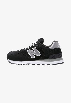 Zwart-grijze New Balance sneaker met witte veters en logo, met een gedempte zool en een bovenwerk van mesh en suède voor casual gebruik.