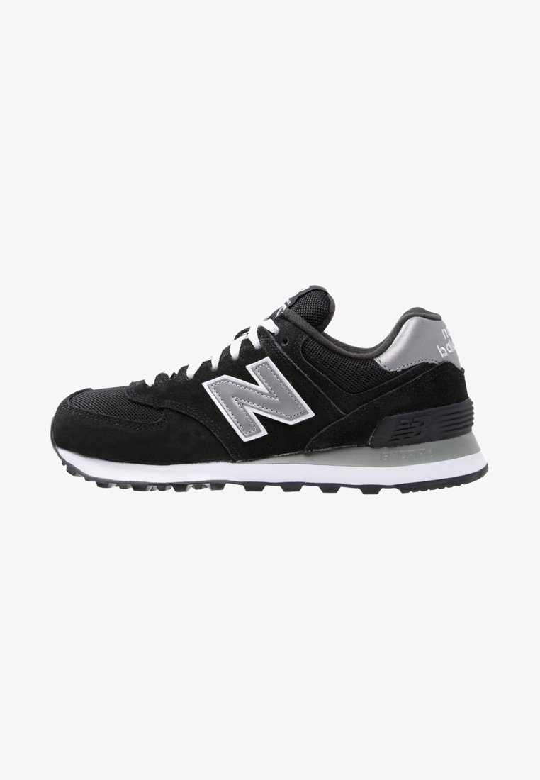 Baskets New Balance noires et grises avec lacets blancs et logo, semelle amortie, dessus en mesh et en suède pour un usage casual.