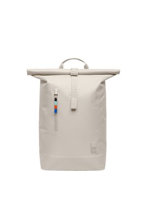 Sac à dos beige clair à rabat enroulable avec poche zippée verticale à l'avant et tirette zippée bicolore, marqué "GOT BAG" en bas à droite.