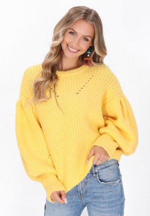 Felle gele gebreide trui met een losse pasvorm, ribbeltextuur en ballonmouwen. Bevat decoratieve gaten bij de halslijn. Casual stijl.