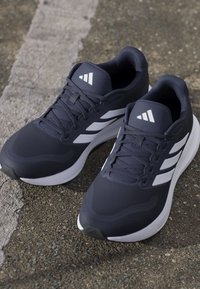 Athletic shoes in dark navy with white accents, featuring a textured upper, lace closure, and a cushioned sole for comfort.