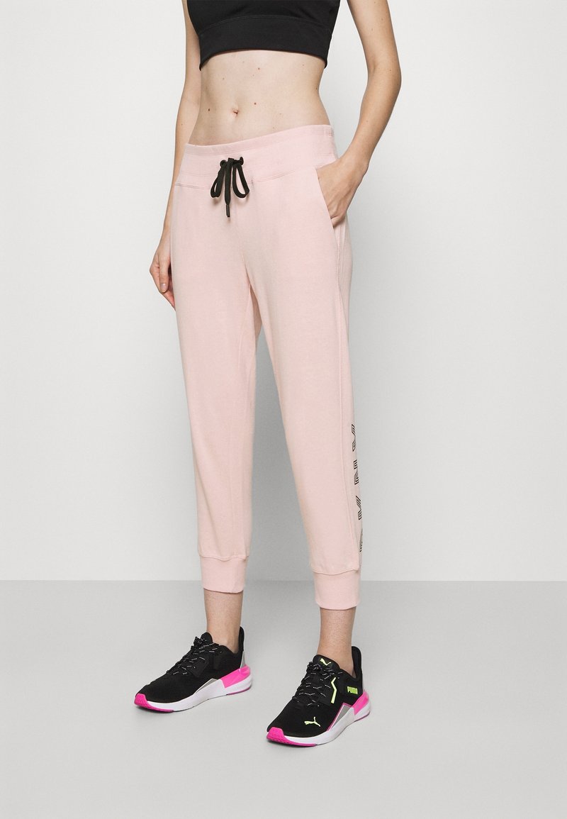 Ljust rosa joggerbyxor med svart dragsko, sidofickor och smalnande mudd. I kombination med svarta och rosa sneakers med neonlysande detaljer.