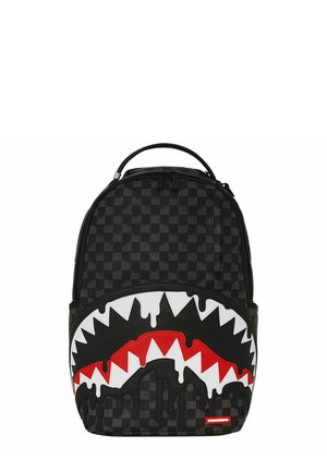 Zaino a scacchi neri con design grafico di bocca di squalo frastagliata bianca e rossa, effetto vernice nera che cola e maniglia superiore.