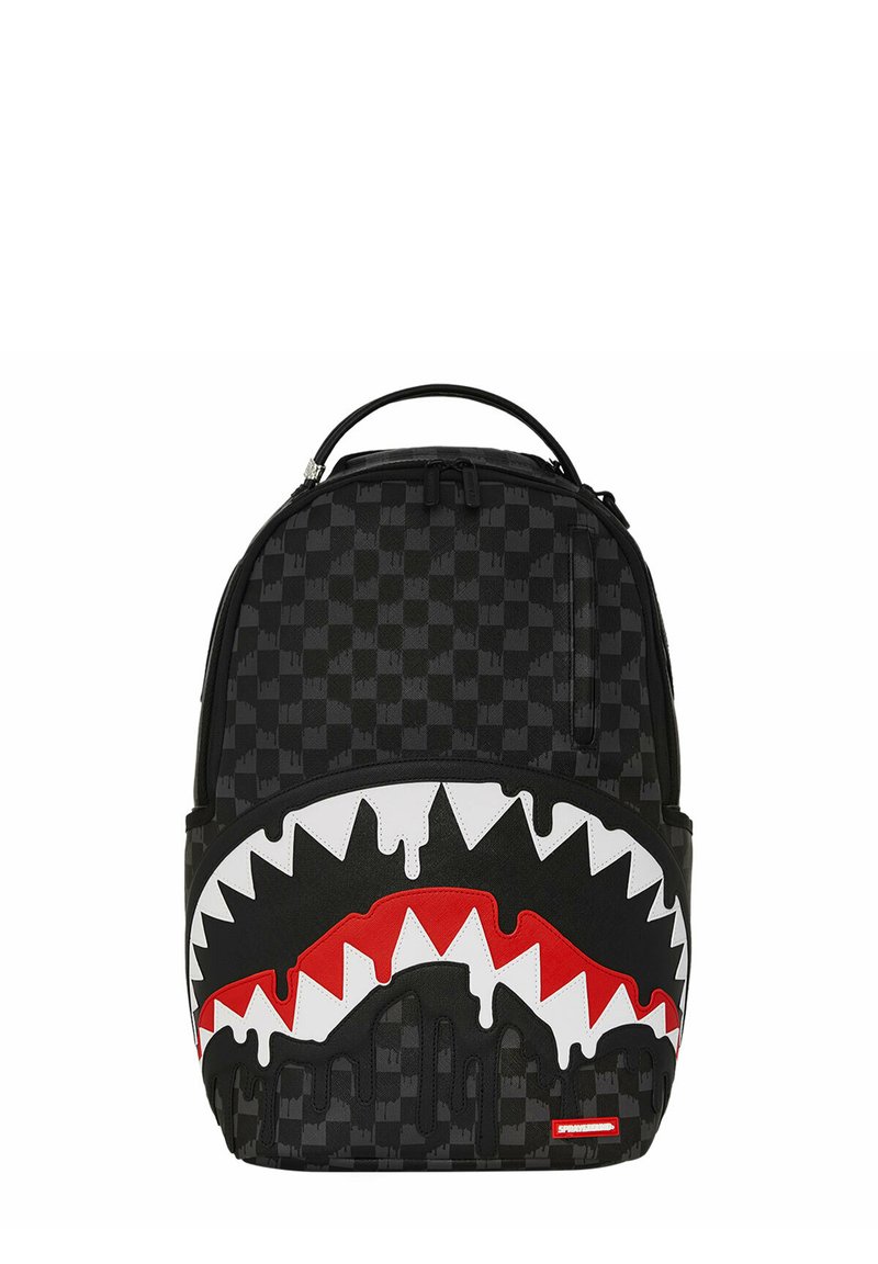 Mochila de cuadros negros con un diseño gráfico de boca de tiburón blanca y roja con bordes dentados, efecto de pintura negra que gotea y asa en la parte superior.