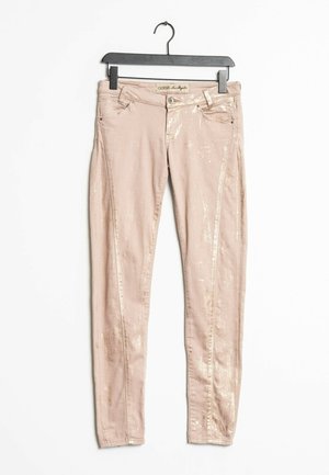 Jeans skinny metálicos rosas con una textura suave, que cuentan con bolsillos frontales y cierre de cremallera. Se cuelga de una percha de plástico negra.