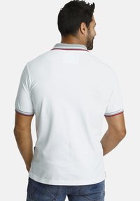 Weißes Poloshirt mit grauem Kragen und roten Akzenten an den Ärmeln. Der Stoff wirkt glatt, mit einer lockeren Passform und kurzen Ärmeln.